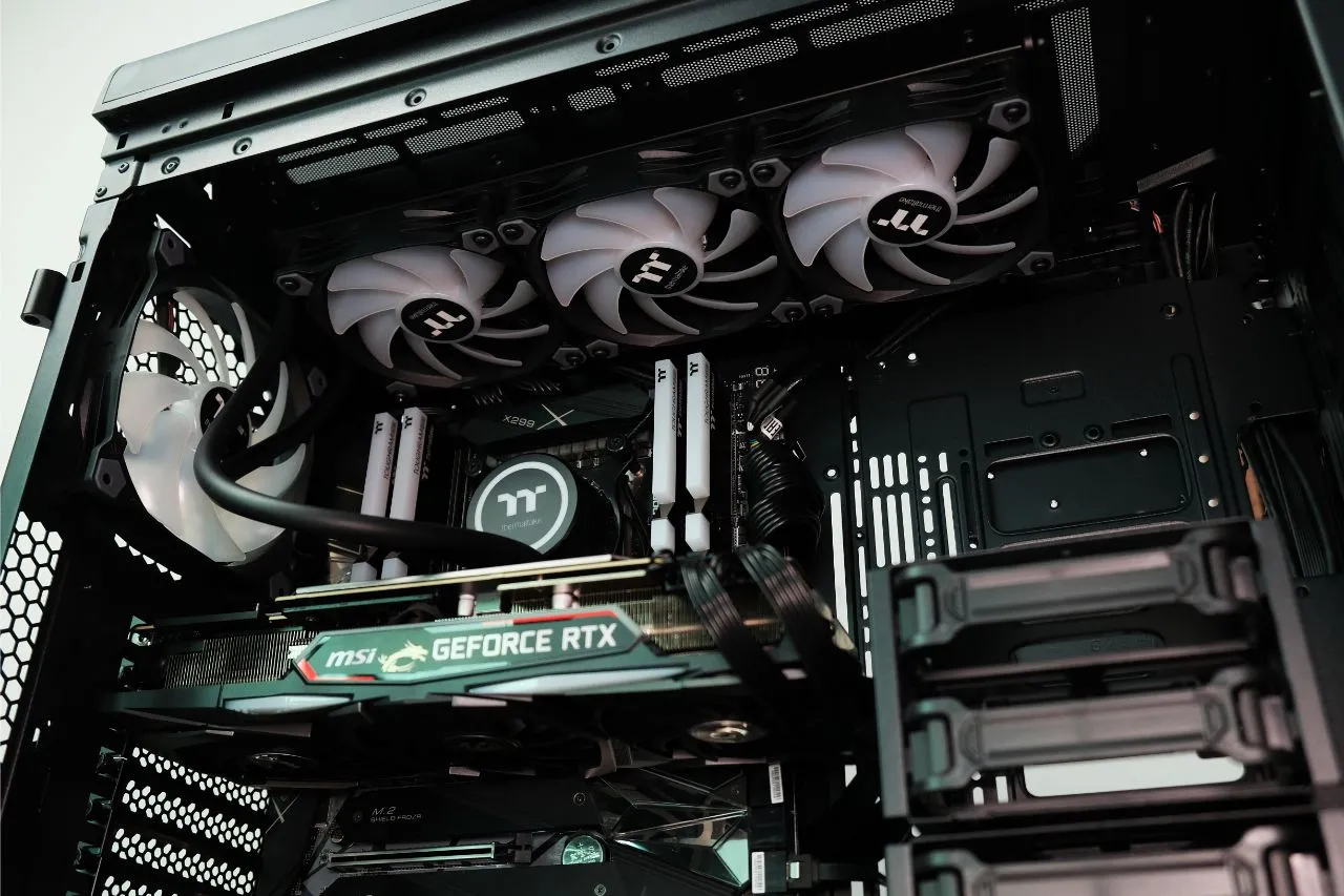 alt=Thermaltake liquid cooler with RGB lighting installed in a PC case.