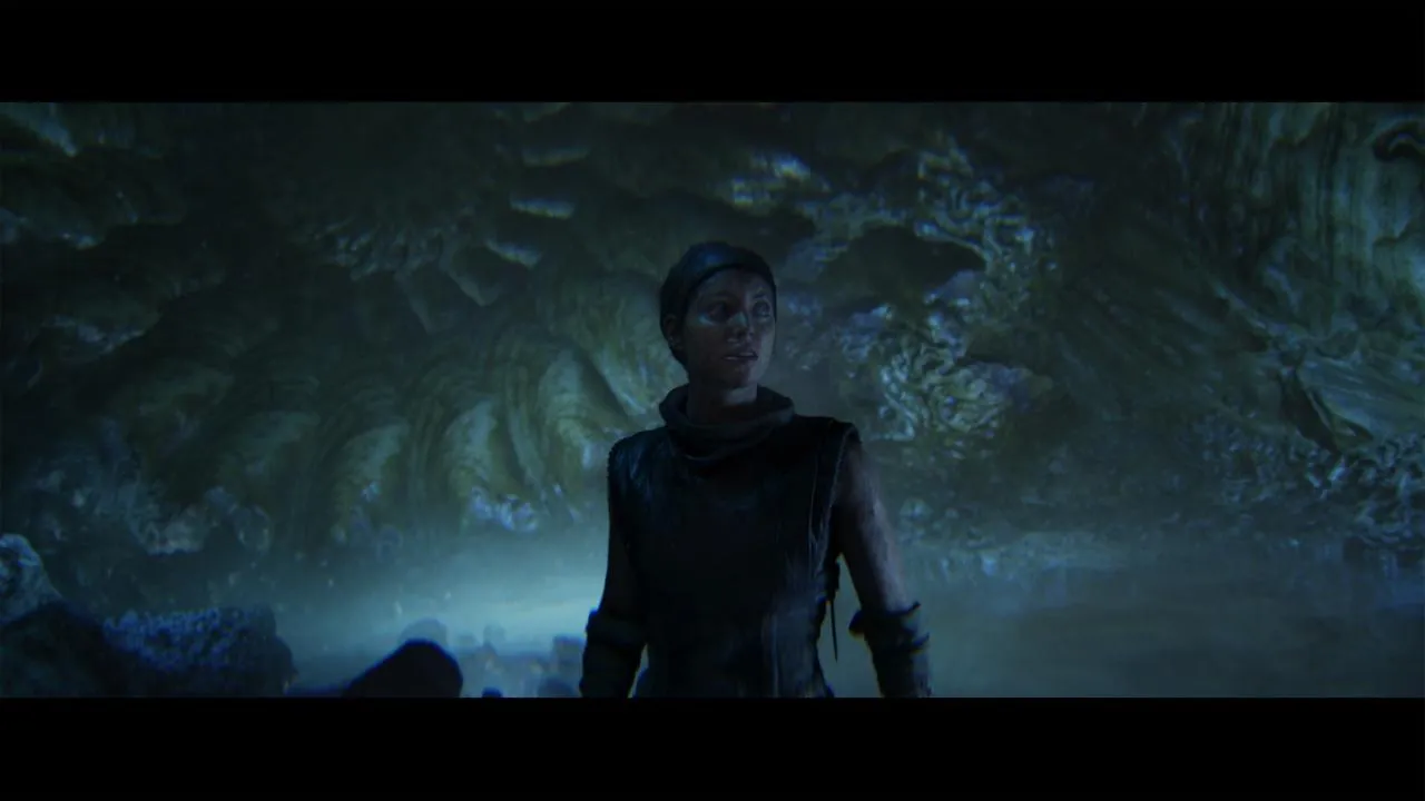 Senua with a drawn sword in a dimly lit environment.